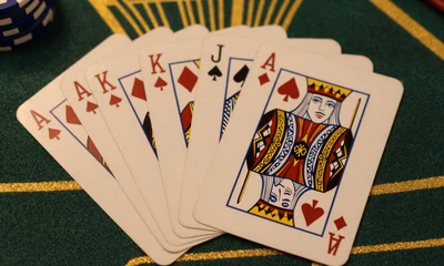 F&auml;cherf&ouml;rmig ausgebreitete Spielkarten auf gr&uuml;nem Casino-Tisch mit Goldlicht