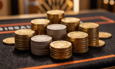 Goldene Casino-Jetons gestapelt auf schwarzem Tisch mit Art-Deco-Beleuchtung